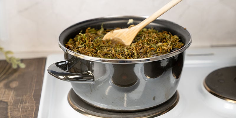 Roer tijdens het koken regelmatig met de houten spatel door het mengsel en vul het bij met heet water zodra de inhoud tot de helft van het oorspronkelijke volume is geslonken.