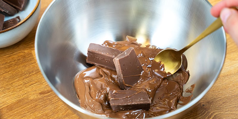 Zodra de chocolade gesmolten is, haal je de kom van het vuur en voeg je weer ¼ toe