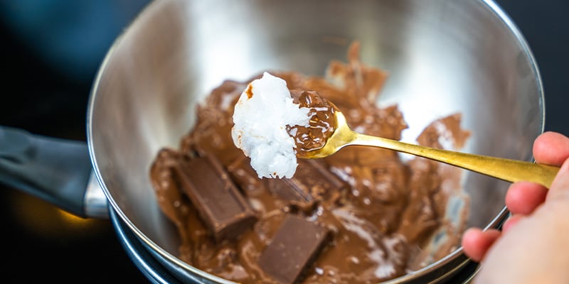 Zodra de chocolade gesmolten is, haal je de kom van het vuur en voeg je weer ¼ toe Voeg nu je cannabisolie of -boter toe