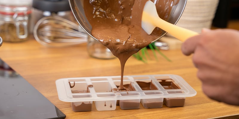 Zodra de chocolade gesmolten is, haal je de kom van het vuur en voeg je weer ¼ toe Voeg nu je cannabisolie of -boter toe Giet de chocolade in een vorm